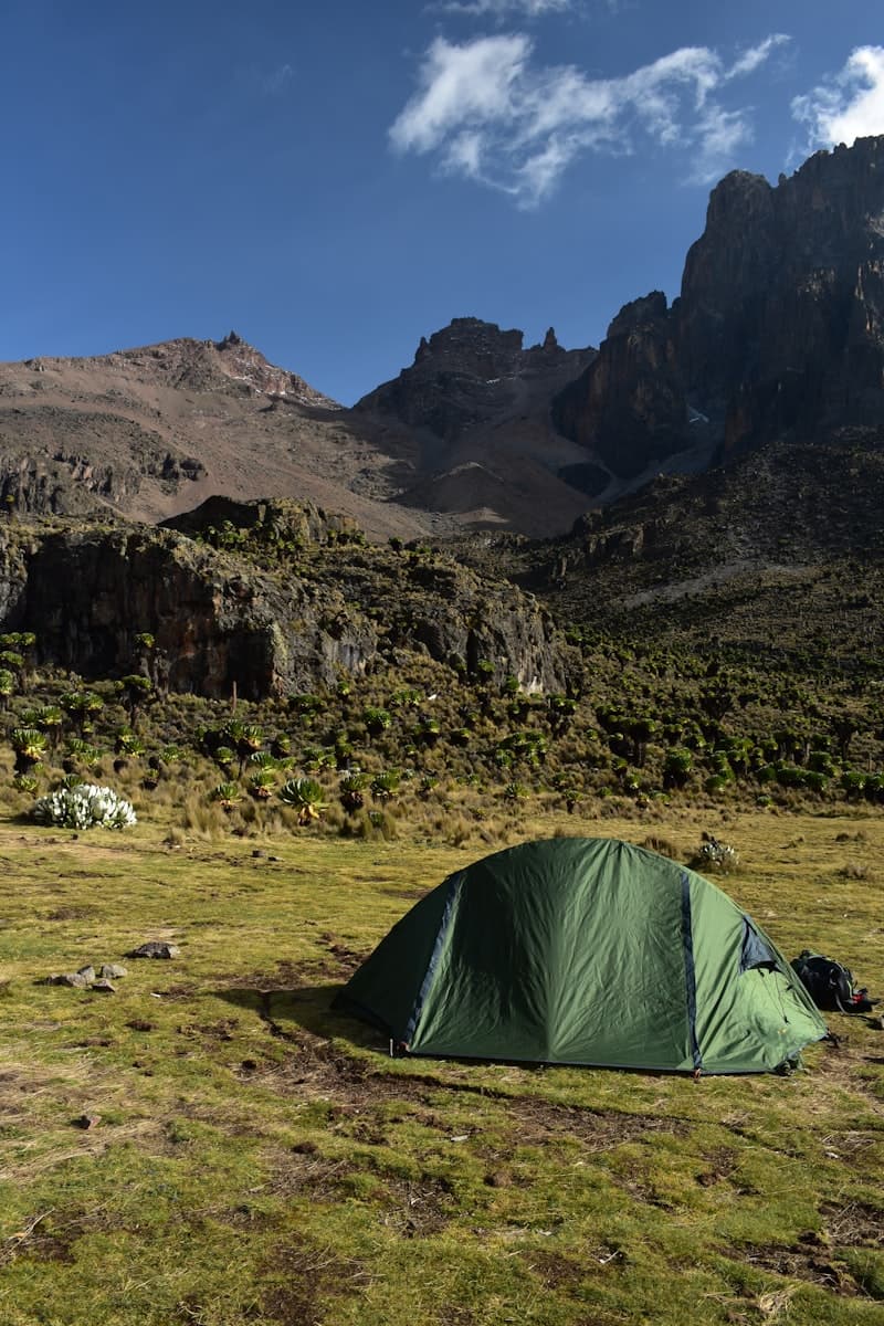 Green dome tent pitched at high camp in mountain hills