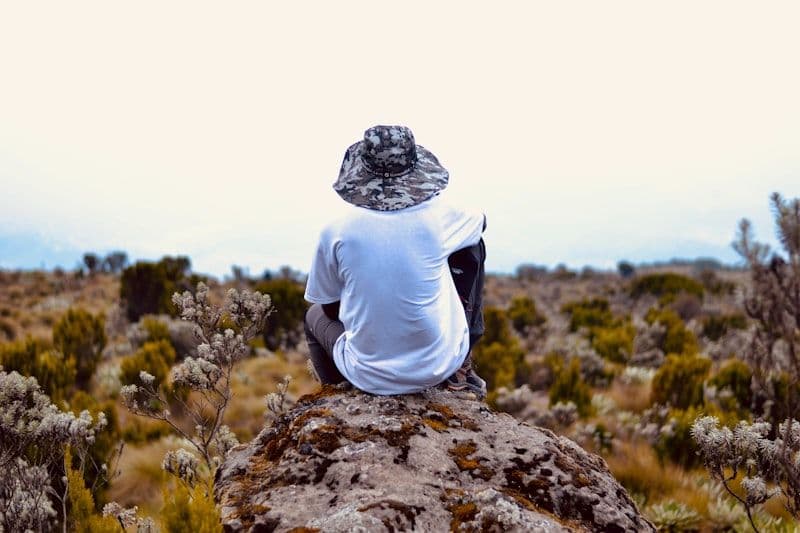 Trekker seated on a high rock surveying a wide mountain landscape