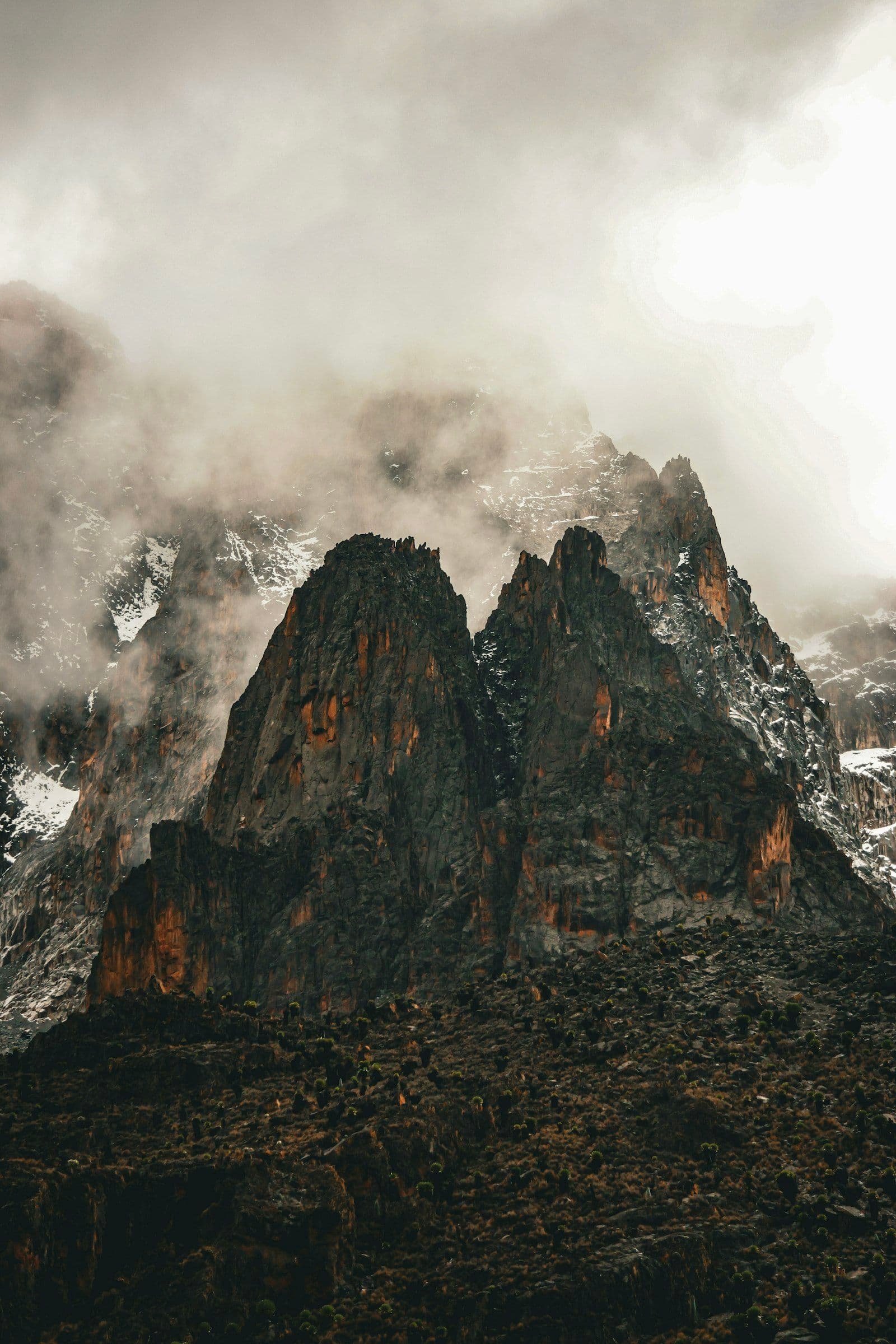 Jagged twin peaks of Mount Kenya — Nelion and Batian — shrouded in mist and dramatic cloud